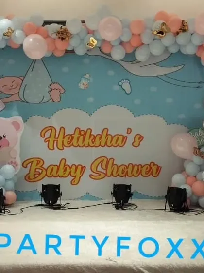 Hetiksha's baby shower featuring a custom backdrop with teddy bear illustrations and a pink and blue balloon arrangement.