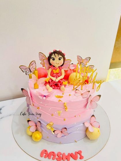 A whimsical fairy cake with pink and purple ombre frosting, decorated with fluttering butterflies.