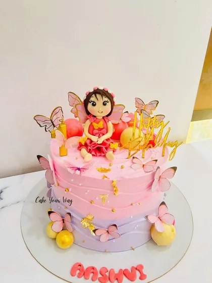 A whimsical fairy cake with pink and purple ombre frosting, decorated with fluttering butterflies.