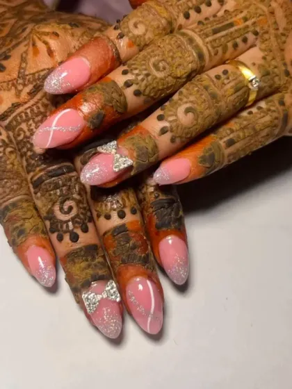 Pretty in pink for a special occasion. These almond-shaped extensions feature a soft pink glitter base, delicate white line art, and adorable 3D rhinestone bow charms.