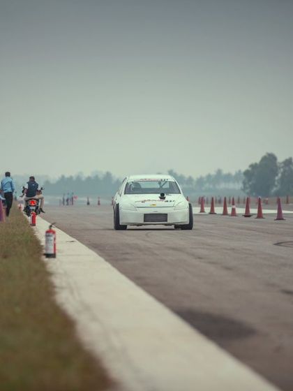 Another view of the white sedan at the start, offering a glimpse of the long, open track ahead. This is the racer's perspective.