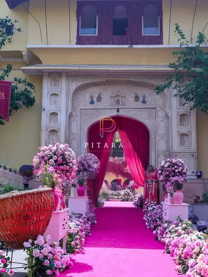 The full view of the grand entrance aisle, showing how the pink carpet leads the eye towards the palace archway. The symmetrical arrangement of floral urns creates a powerful sense of arrival.