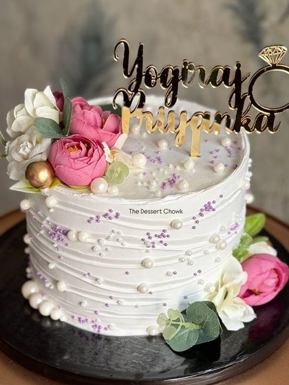 A beautiful engagement cake with textured white buttercream, fresh flowers, and a custom name topper. It's simple, elegant, and romantic.