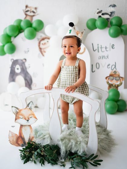 A big smile from the birthday boy in his cute gingham romper.