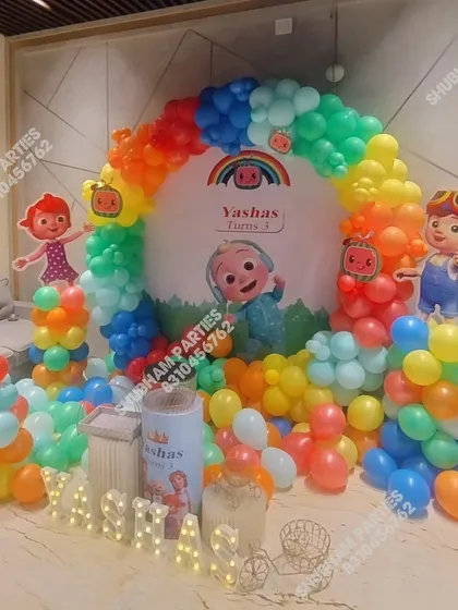 A Cocomelon themed balloon ring decoration, perfect for home celebrations. The setup includes character cutouts and marquee letters for the child's name.