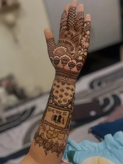 A clear shot of the forearm design, highlighting the custom silhouette and wedding date. The surrounding patterns of lotus buds and jaali work complement the central theme.
