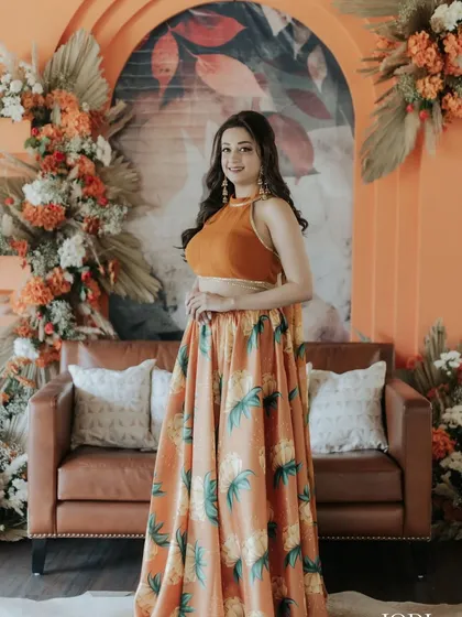 The client posing against a beautiful floral backdrop. Her soft, wavy hair complements the festive decor perfectly.
