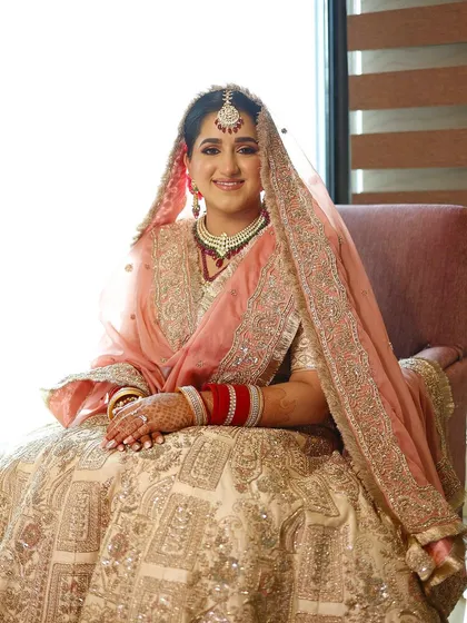 The bride seated, looking serene and beautiful. The peach-toned makeup enhances her natural radiance.