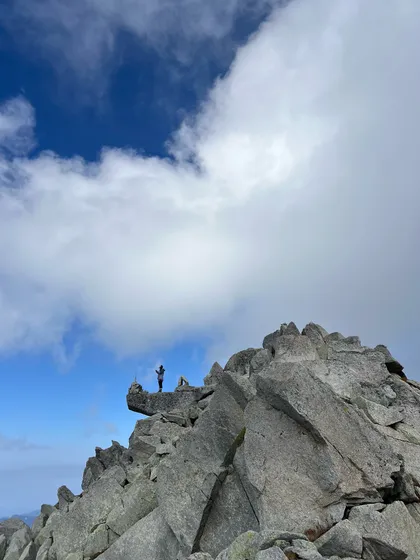 Standing on the rocky summit of Minkiani Pass. This offbeat trek offers breathtaking views and a sense of solitude.