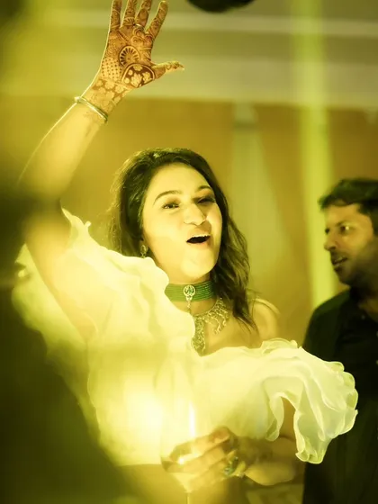 A guest lost in the music on the dance floor. The yellow lighting and candid expression make this a vibrant and energetic party shot.