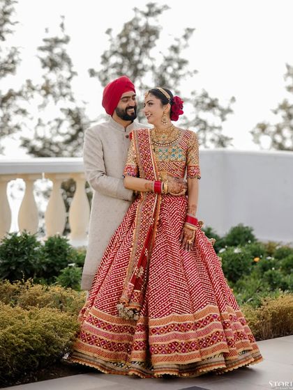 A classic portrait of Rohit and Mehak against a scenic backdrop, her red lehenga contrasting beautifully with his subtle attire.