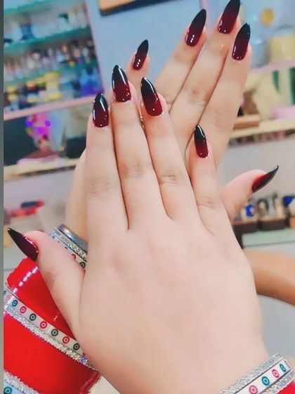 A dramatic black and red ombre effect on sharp stiletto nails. This design is perfect for a bold, vampy look, especially when paired with traditional attire like these bridal bangles.