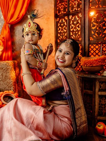 A heartwarming portrait of a mother holding her Little Krishna, both sharing a beautiful smile.