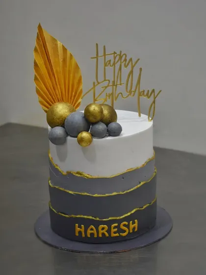 A tall, dark, and handsome cake for Haresh's birthday. This design features a grey ombré effect with gold-lined edges and is topped with a golden palm spear and spheres for a sophisticated look.