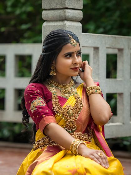 A close-up of the model's beautiful jewelry and the rich texture of her yellow silk saree.