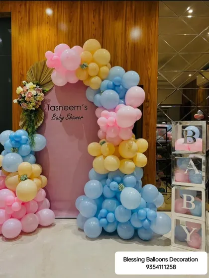 A closer look at a modern pastel-themed baby shower decoration. The combination of a custom backdrop, an organic balloon garland, and transparent 'BABY' blocks creates a chic and stylish celebration.