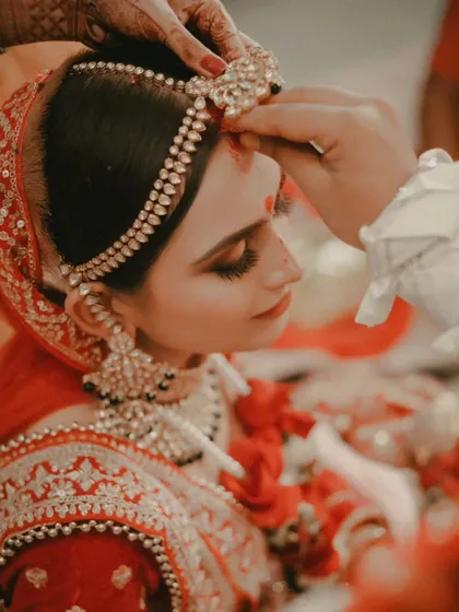 A close-up of a sacred wedding ritual, where sindoor is applied to the bride's forehead, a powerful and symbolic moment.