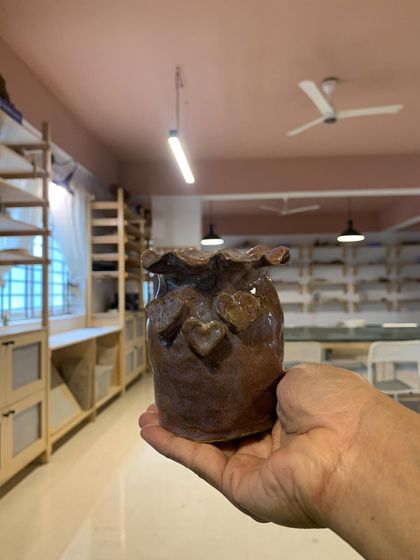 A rustic, heart-covered pot held in front of our studio. This piece, made by a young student, is a heartwarming reminder of the joy and love that is poured into the work here.