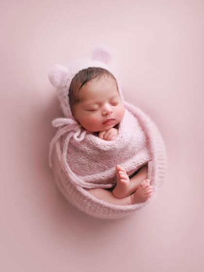 This little strawberry baby is all tucked into a pink knit cocoon, complete with a matching bear-ear bonnet. It's a perfect example of a fun, themed pose.