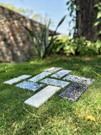 To truly understand a material, we place it in its future context. Here, terrazzo tile samples are laid on the grass at a project site. This allows us to assess how each surface reacts to natural light and coexists with the native landscape.