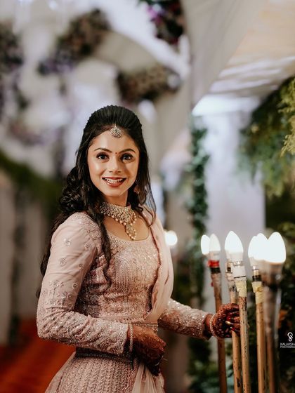 A candid portrait of a bride in a lovely pink lehenga, captured in a moment of quiet happiness.