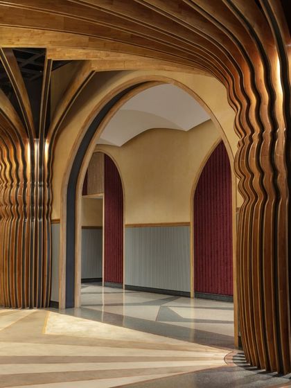 A detail of the custom-fabricated columns at Nishtara, which flow upward into the vaulted ceiling. The rhythmic, undulating form of the rubberwood profiles softens the grand scale of the hall and adds a layer of intricate craftsmanship.