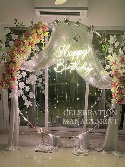 A closer look at the elegant floral and drape arch. The combination of pink and white roses, white leaves, and sheer fabric creates a soft and sophisticated backdrop, perfect for a milestone birthday.