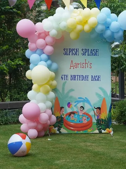 A wider view of the outdoor pool party setup, showing the backdrop, balloons, and a beach ball to complete the scene.