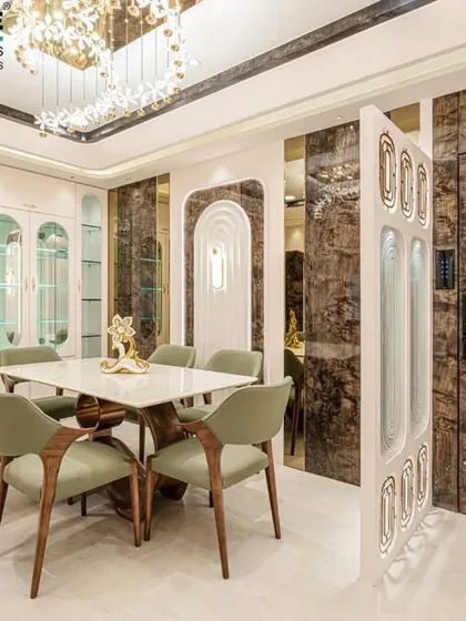 A beautiful dining setup in Seawoods, featuring green upholstered chairs and a marble-top table. The design includes a built-in crockery unit and decorative wall paneling with marble and mirror finishes.