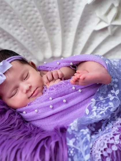 Another angle of the purple shell theme, capturing the newborn's peaceful expression and tiny feet peeking out from the swaddle.