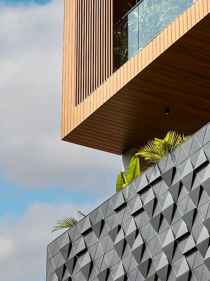 This modern facade showcases innovative design through diverse materials. Sleek wooden panels with edgy corners and glass railings create a contemporary aesthetic, while 3D geometric panels add a dynamic, texturally rich layer.