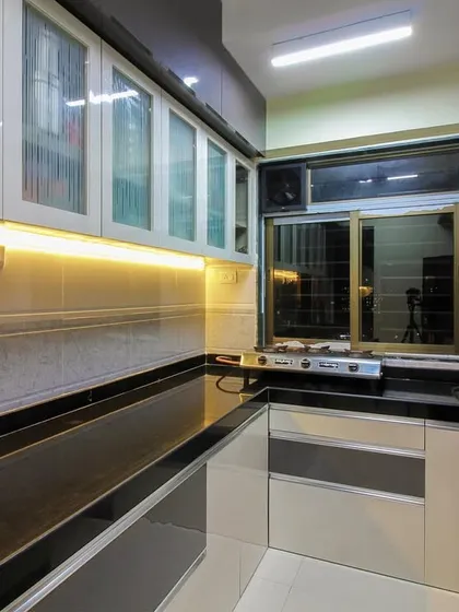 A practical kitchen with a black granite countertop and a mix of grey and white cabinets. The frosted glass on the upper cabinets adds a touch of lightness to the design.