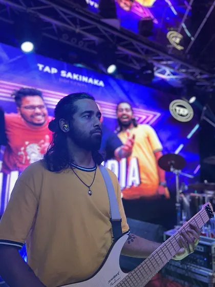 Our guitarist, lost in the music with our band's visuals on the big screen behind him. He wows the audience with electrifying solos and captivating riffs.