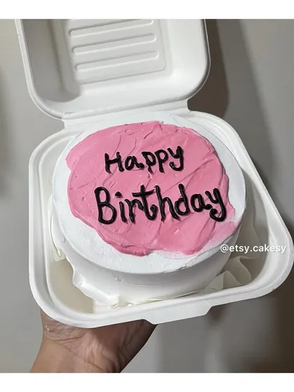 A simple pink and white bento cake with 'Happy Birthday' written in a casual, bold font.