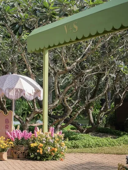 The welcome signage for the 'Riverside Brunch', set amidst lush greenery and colorful flower arrangements.