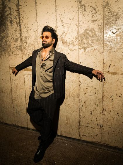 Rithvik Dhanjani in a dynamic pose, wearing our coat-collared striped brown jacket. The tropical wool fabric and modern details make this a standout piece.