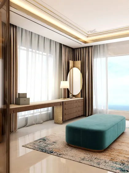 A view from the master suite into the luxurious bathroom and dressing area. The space is designed for openness, with large windows providing natural light and a sea view, while a teal ottoman adds a pop of color to the neutral palette.