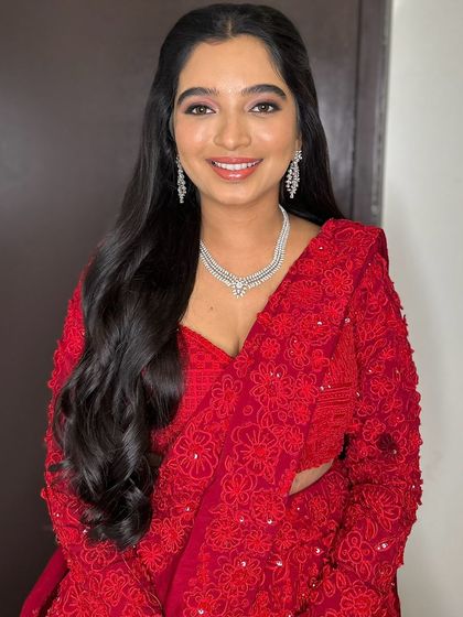A classic open hairstyle with soft waves, perfect for this client's stunning red lehenga.