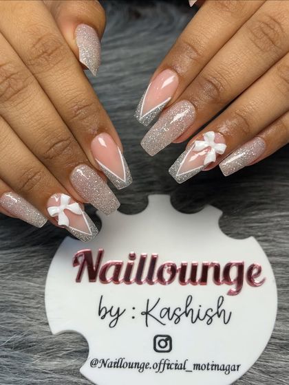 A beautiful coffin-shaped set featuring glitter nails with white V-tips and delicate 3D bow accents.