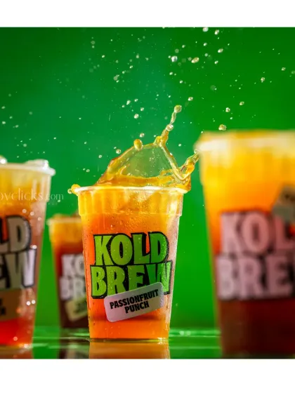 A dynamic splash shot of a passionfruit punch cold brew, capturing the moment of impact to create a refreshing and visually exciting beverage photo for Greed Coffee.