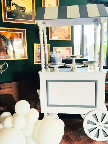 A classic white cart serves as a stylish cake or dessert station, fitting perfectly with the elegant and clean aesthetic of the event.