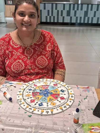 The satisfaction of completing a beautiful piece of art. This participant in our corporate workshop is happy with her colorful and intricate Lippan creation.