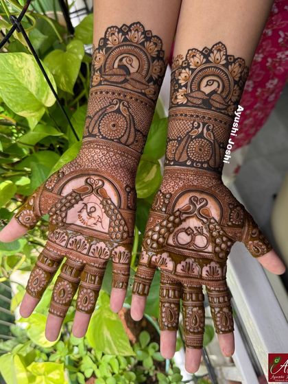 A shot of the peacock-themed engagement mehendi against a natural green background, highlighting the fresh henna application.