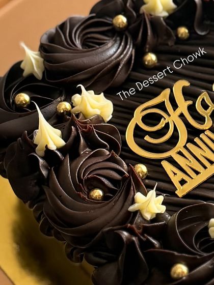 A rich chocolate truffle anniversary cake with intricate dark and white chocolate piping.