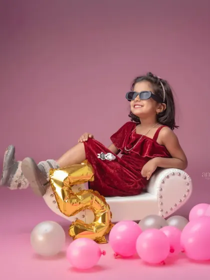 A fun and sassy pose for a fifth birthday celebration. The birthday girl leans back in a chair with sunglasses on, showing off her personality in this cool and creative shot.