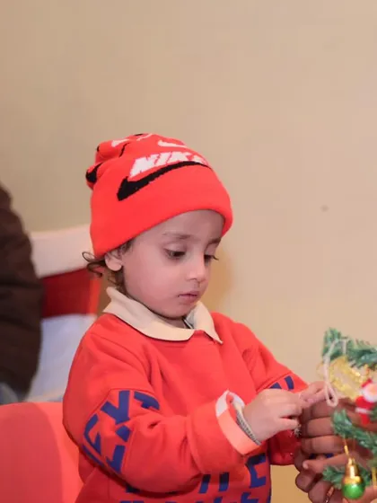 A young child carefully placing an ornament on a tree during our Christmas event. These activities are great for developing fine motor skills.