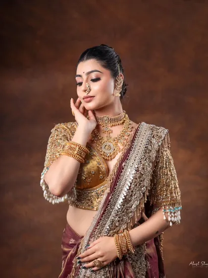 A moment of grace in a traditional bridal look. The model's soft expression and the rich gold jewelry create a timeless and beautiful portrait.
