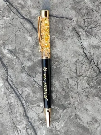 A close-up of my popular gold flake pen, personalized with the name 'Abdul M.G'. The gold flakes inside the pen add a touch of luxury.