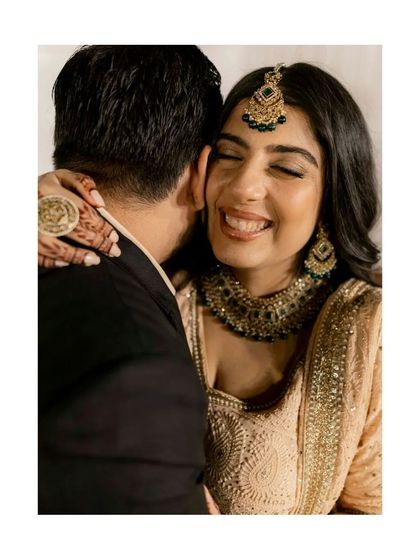 A beautiful, happy bride gets a warm hug from her groom. Her joyful, eyes-closed smile says it all.