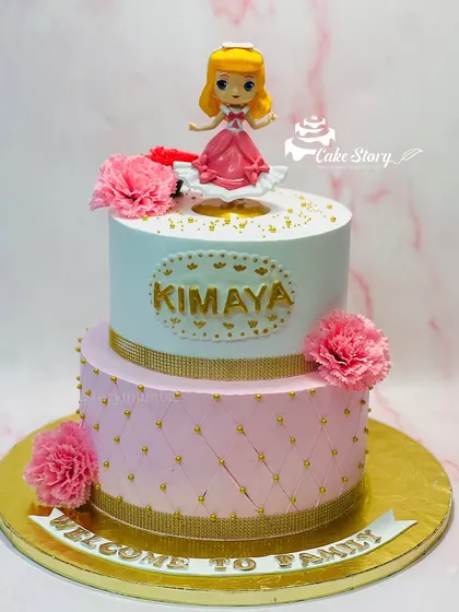 A cake fit for welcoming a new princess to the family. This two-tier pink and white cake features a quilted pattern, gold details, and a doll topper.
